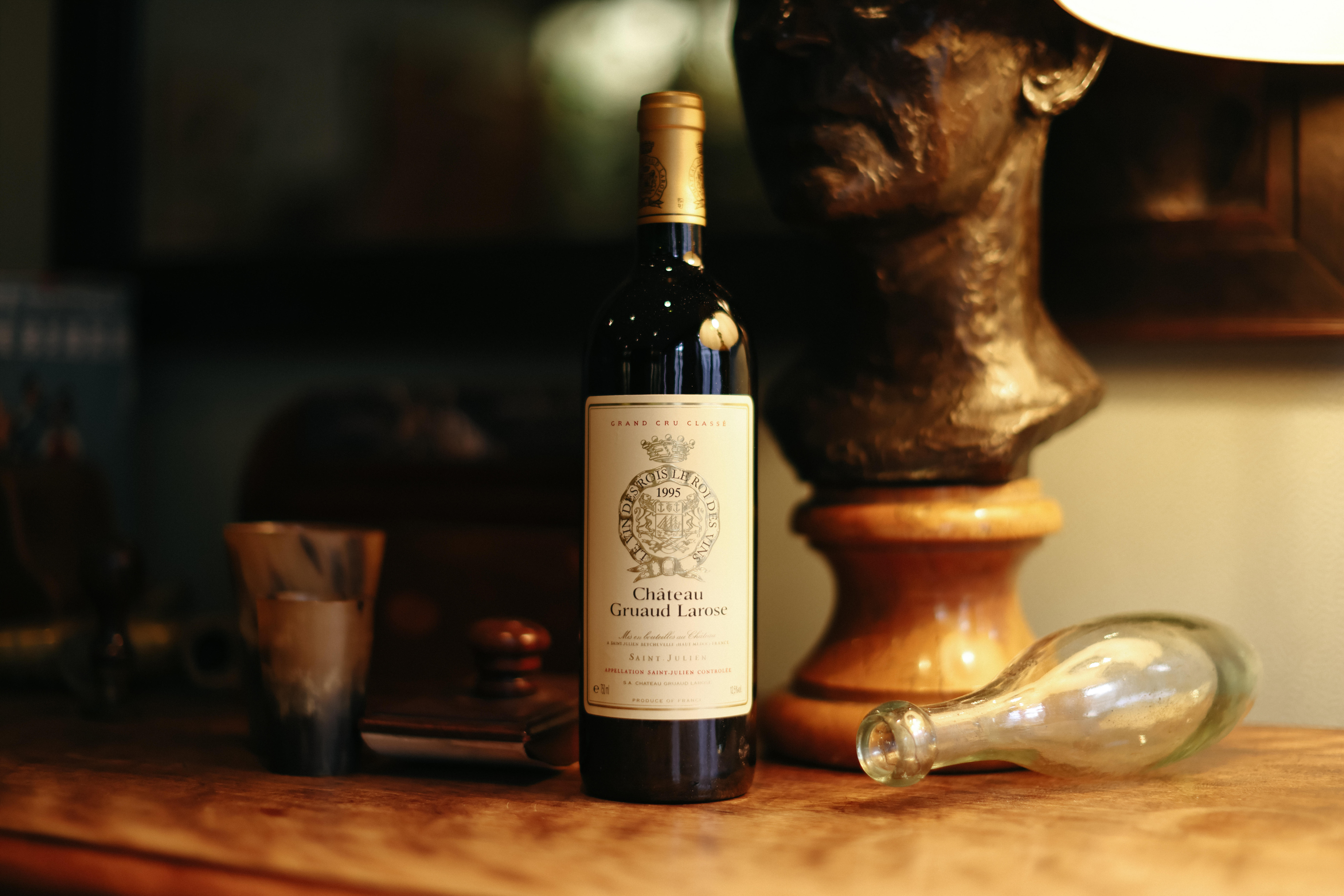 A bottle of Gruaud-Larose, upright and unopened, in front of decorative sculptures
