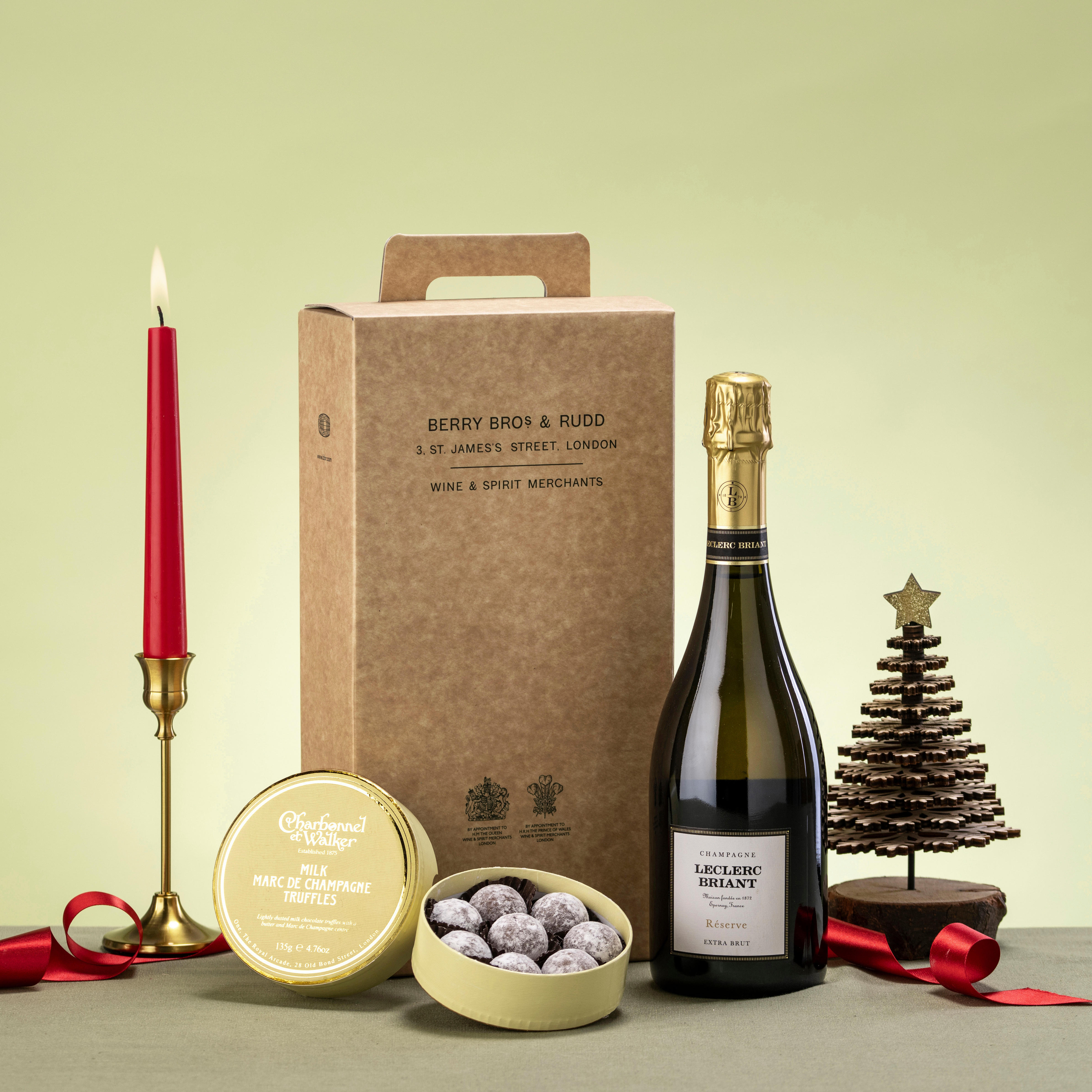 A bottle of Champagne with a box of chocolates with a cardboard gift box. 