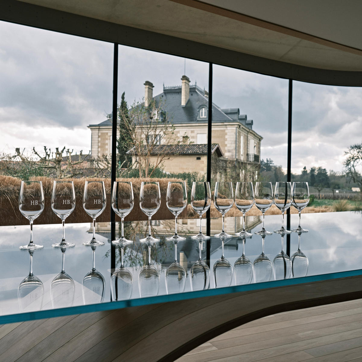 The view from the tasting room at Château Haut-Bailly; glasses are lined up on a table and the château building is visible in the background.