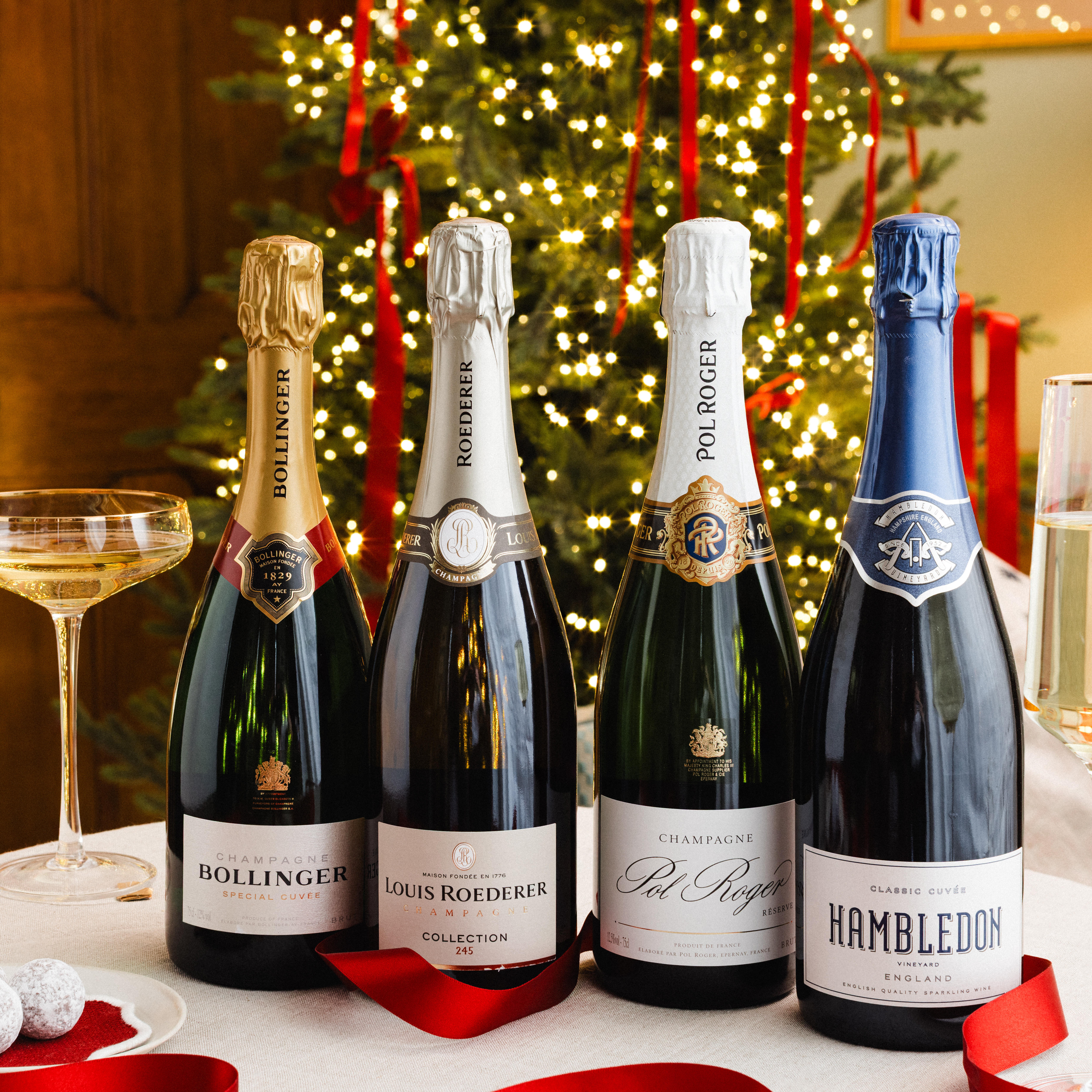 4 bottles of sparkling wines against a festive Christmas tree.