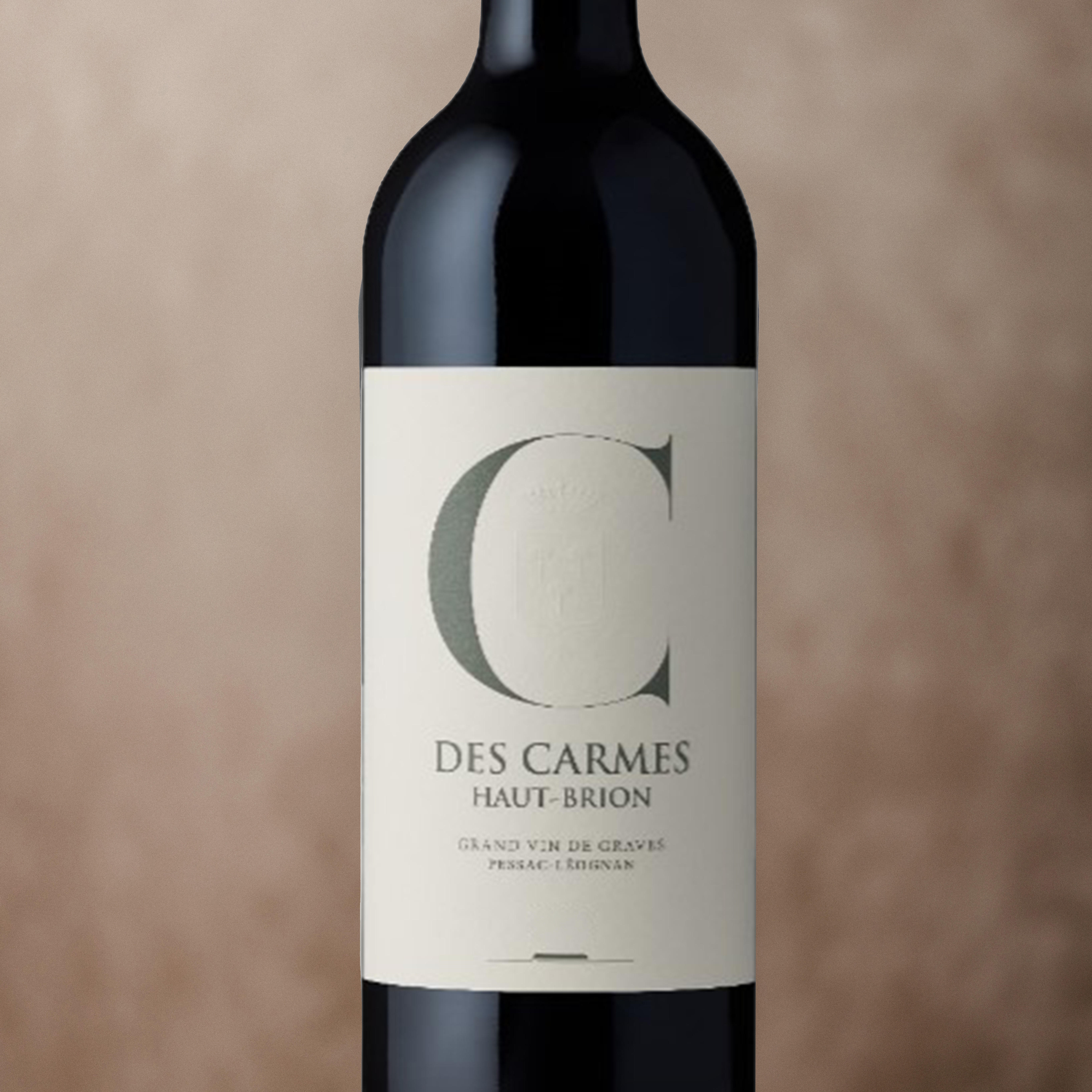 A bottle of 2022 Le C des Carmes Haut-Brion wine with an elegant label featuring a large letter C and text grand vin De Graves Pessac-Léognan.