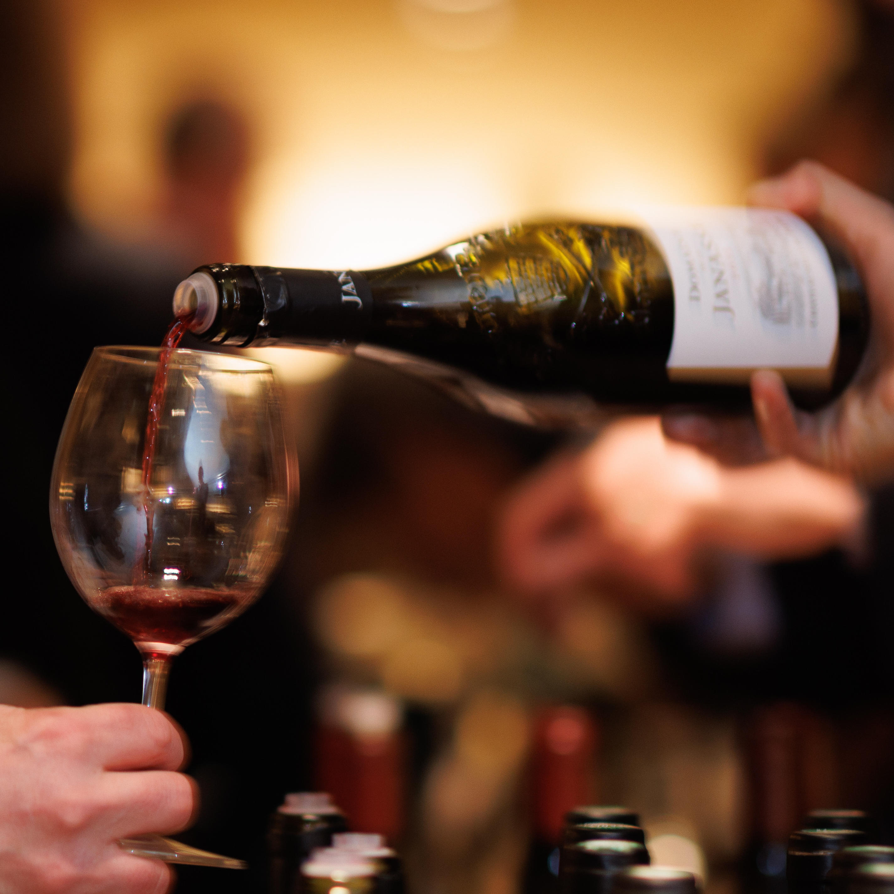 A close-up of a wine bottle pouring red wine into a glass, promoting the Berry Bros. & Rudd Cellar Plan.