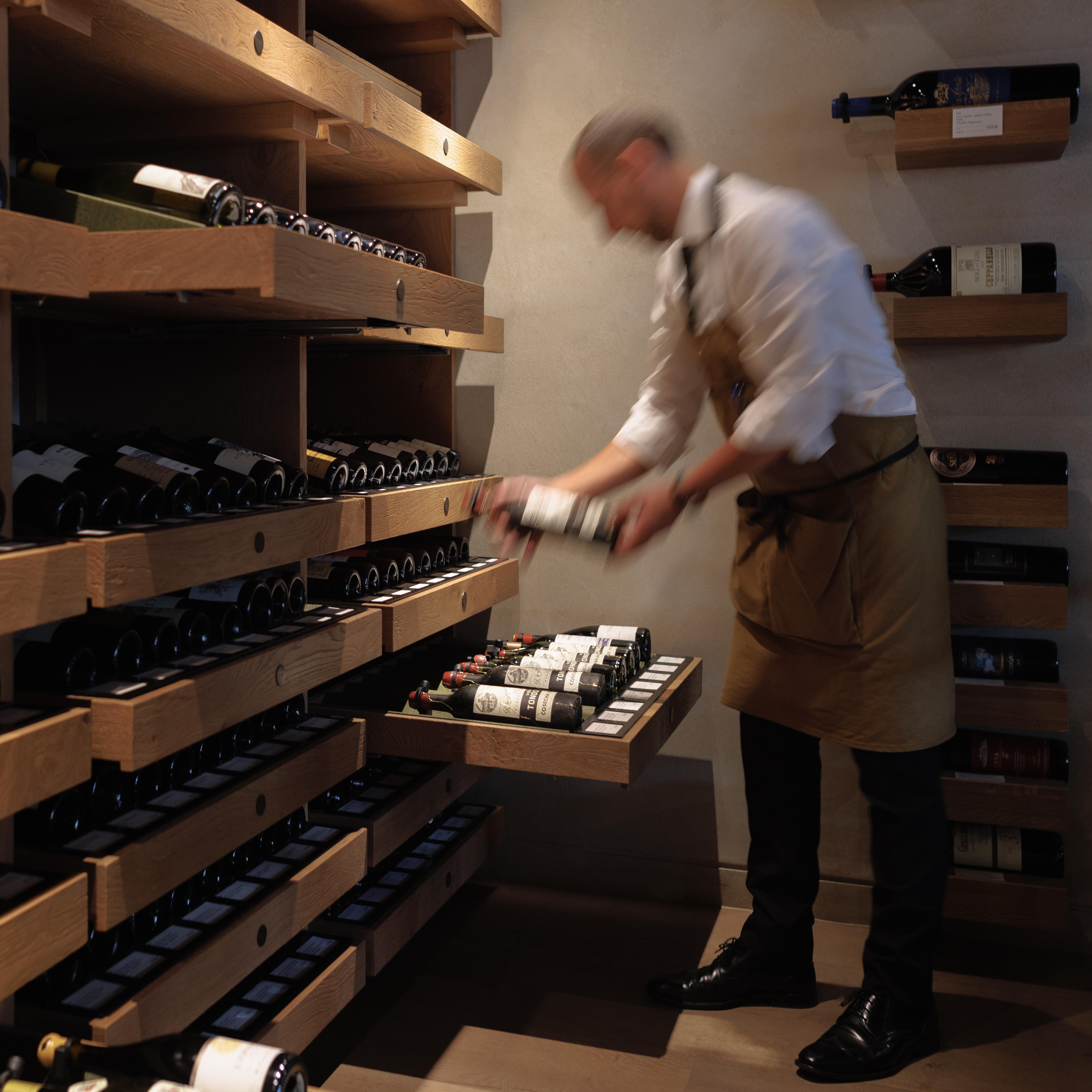 Berry Bros. & Rudd staff member arranging bottles in a cellar. Latest fine wine releases, available by the case and in limited quantities.