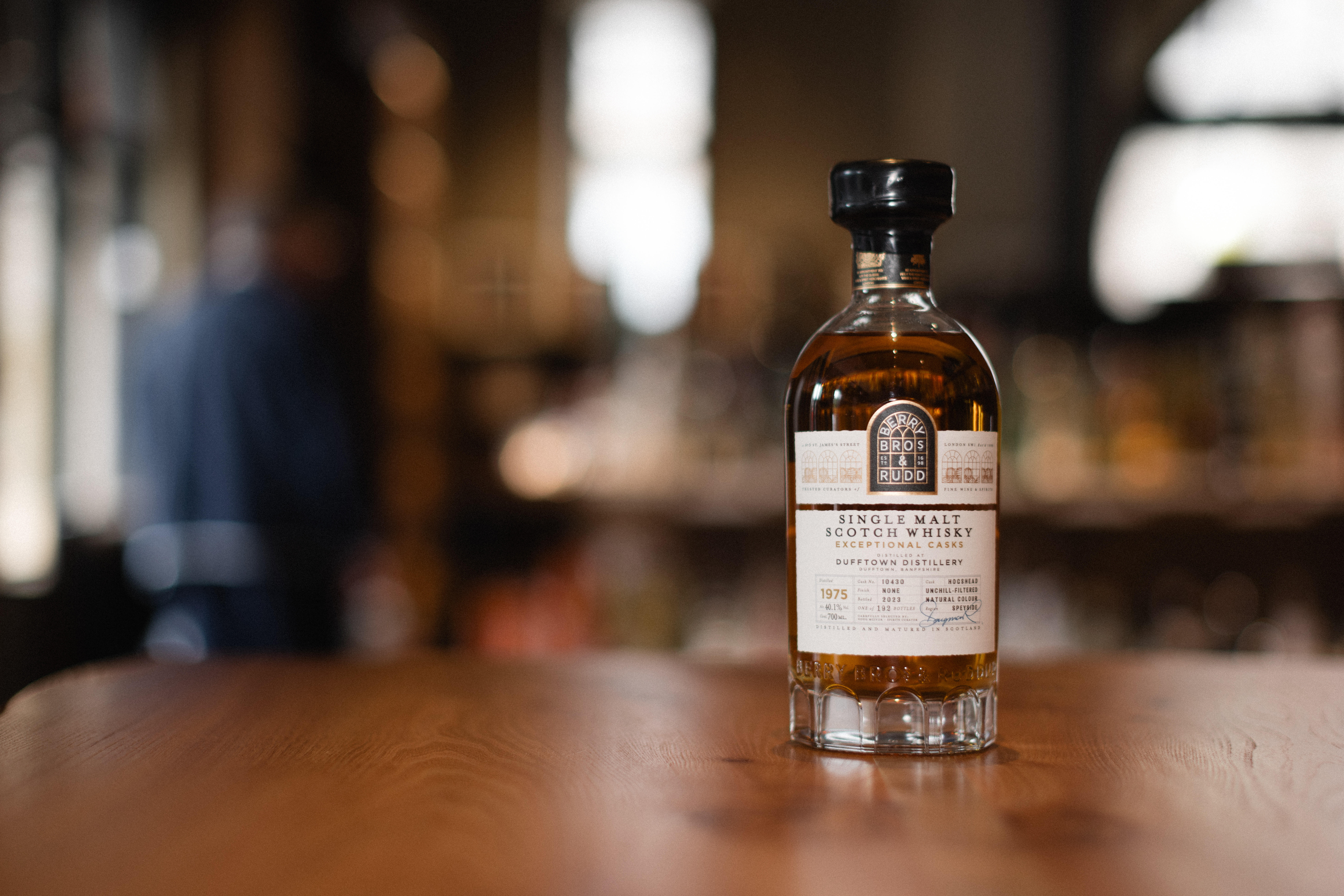 A bottle of The Glenturret 10 Year Old Peat Smoked Single Malt Scotch Whisky on a polished wooden surface, with a soft-focus background.