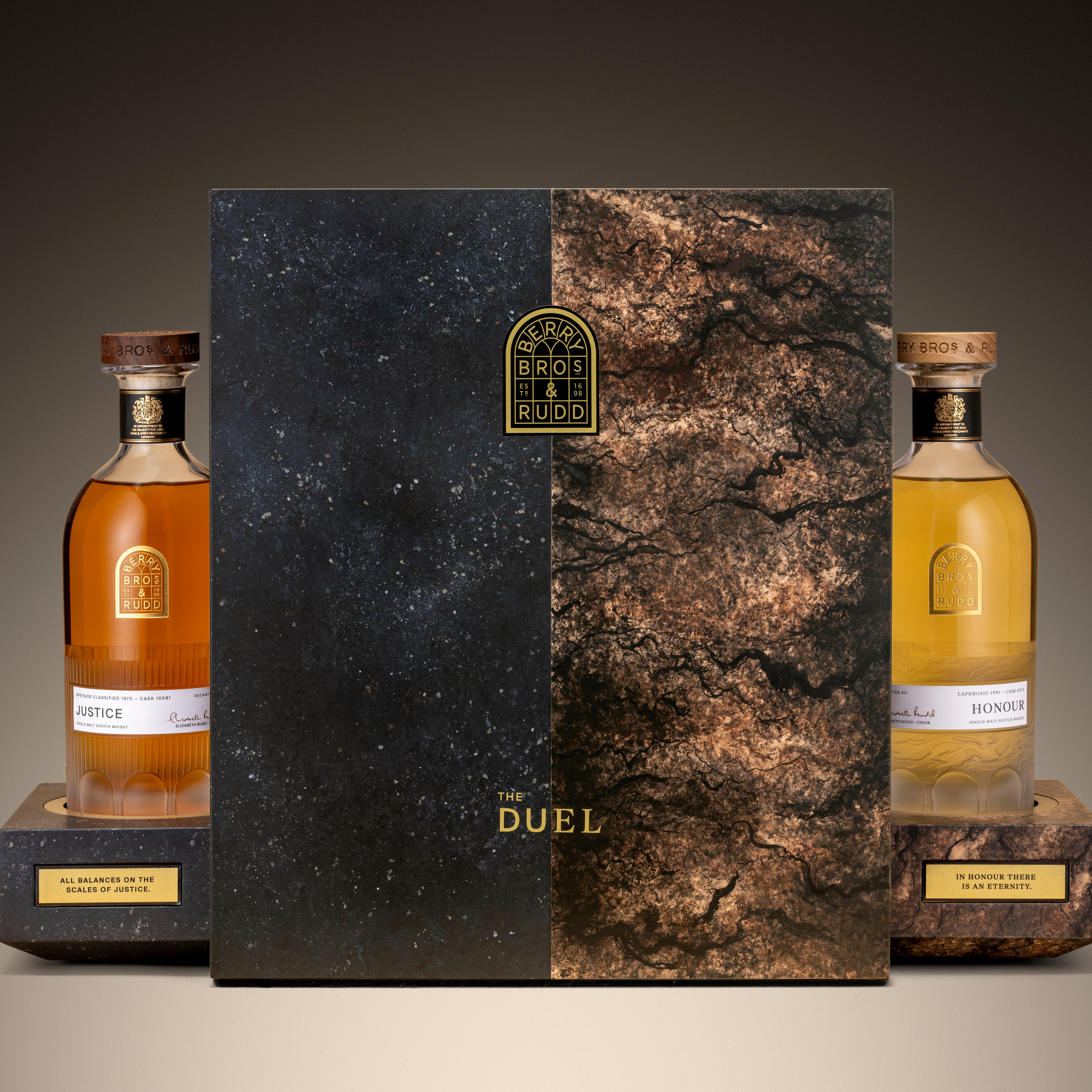 Honour and Justice limited edition whiskies from Berry Bros. & Rudd’s The Duel set, displayed on a stone-textured plinth.