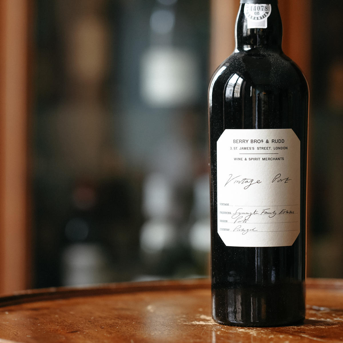 A photo of our Own Selection Vintage Port sitting on top of a wooden table in the Berry Bros. & Rudd General Office; the label is handwritten and states it is made by Symington Family Estate in Porto 